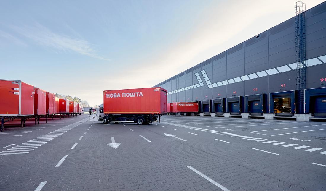 Вантажівка та причепи "Нова пошта" біля логістичного термінала.